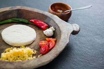 Pizza dough with various ingredients on a wooden tray