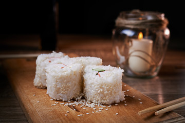 Japanese food, sushi roll with crab, sesame seeds, cucumber, cheese, on a wooden board