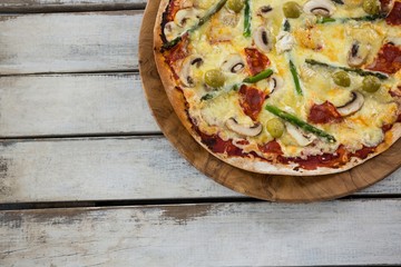 Italian pizza in a chopping board on a wooden plank