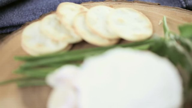 Soft flavored creamy cheese with garlic and fine herbs on a wood board with crackers