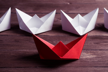 Business leadership concept with white and color paper boats on 