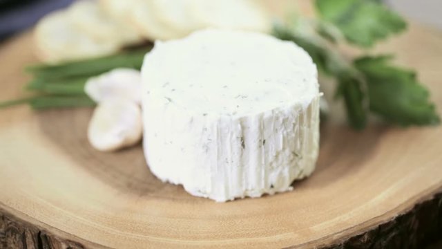 Soft flavored creamy cheese with garlic and fine herbs on a wood board with crackers