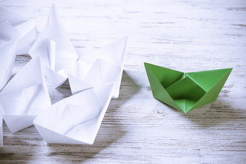 Business leadership concept with white and color paper boats on 