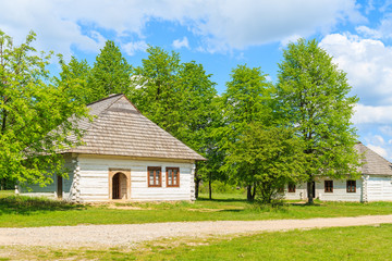 Old traditional houses with straw roofs in Tokarnia village on sunny spring day, Poland