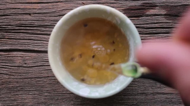 Pouring hot tea from a little Asian pot into a tea cup.