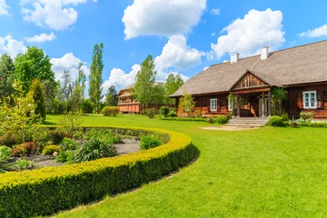 Poster Old traditional manor house and beautiful garden in Tokarnia village on sunny spring day, Poland © pkazmierczak