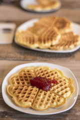 Eating Homemade waffles on white plate with red strawberry jam jelly