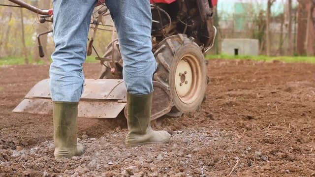 Farmer plowing the field with rototiller. 