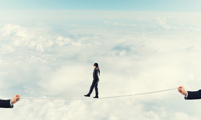 Business concept of risk support and assistance with man balancing on rope