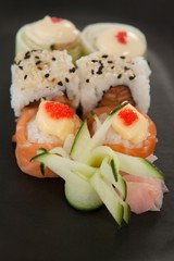 Uramaki and nigiri sushi served in black plate 