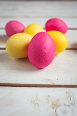 Easter background with yellow and pink eggs . Top view with copy space . Easter eggs on rustic wooden planks