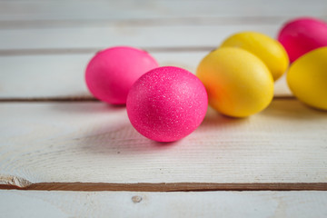 Easter background with yellow and pink eggs . Top view with copy space . Easter eggs on rustic wooden planks