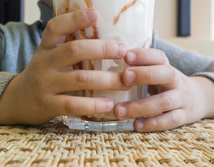 Young boy holding a glass of milkshake. Cropped image.