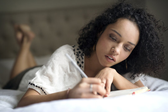 Woman writing in notepad in bedroom