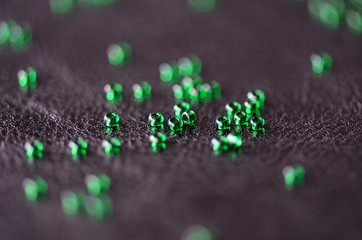 Transparent green seed beads on a dark leather background