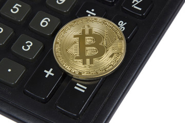 gold bitcoin lies on a black calculator