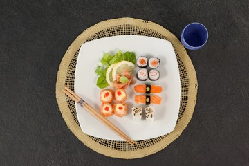 Fototapeta na wymiar Assorted sushi set served with chopsticks and glass on sushi mat