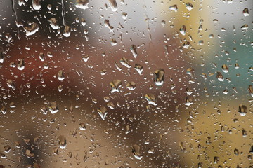 Rain drops on window with house and church in background 