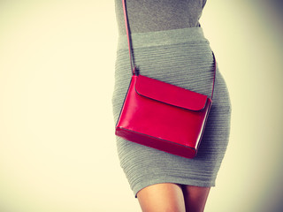 Slim girl in gray skirt with red handbag