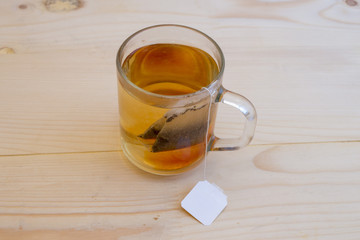 Black tea in a glass cup with tea leaves is on a wooden table. Tea, breakfast