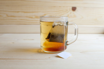 Black tea in a glass cup with tea leaves is on a wooden table. Tea, breakfast