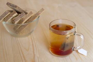 Black tea in a glass cup with tea leaves is on a wooden table. Tea, breakfast