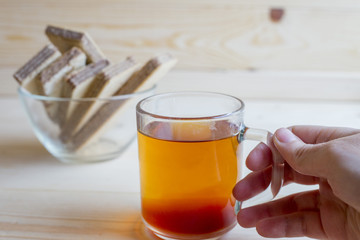 Black tea in a glass cup with tea leaves is on a wooden table. Tea, breakfast