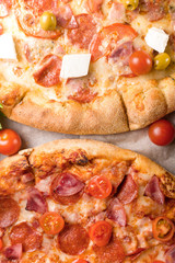 Rustic pizza with salami, mozzarellabasil top view with copy space. Two pizzas on a wooden table. Pizza salami on wooden background. Pizza salami with tomatoes and olives.