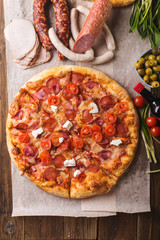 Rustic pizza with salami, mozzarellabasil top view with copy space. Two pizzas on a wooden table. Pizza salami on wooden background. Pizza salami with tomatoes and olives.