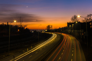 Fototapeta premium Światła samochodów na ulicy podczas zachodu słońca. Długa ekspozycja.