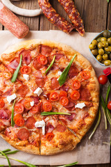 Rustic pizza with salami, mozzarellabasil top view with copy space. Two pizzas on a wooden table. Pizza salami on wooden background. Pizza salami with tomatoes and olives.