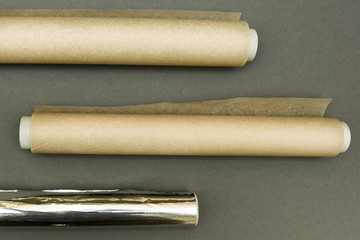 Plastic wraps and roll of aluminum foil on grey background.