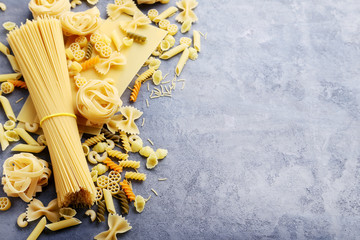 Different kinds of pasta on grey wooden table