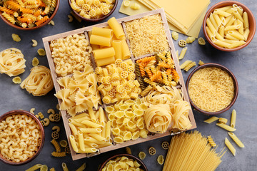 Different kinds of pasta on grey wooden table