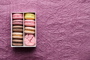 Box of colorful macarons on textured background