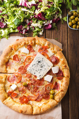 Pizza with blue cheese on a wooden background. Spring pizza. Salad mix