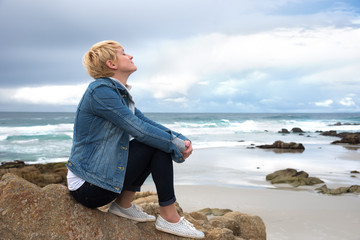 Young women is siting on the rock on beach