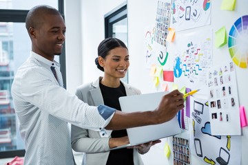 Smiling graphic designers discussing over charts and graph