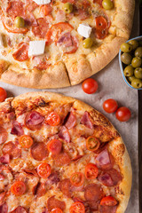 Rustic pizza with salami, mozzarellabasil top view with copy space. Two pizzas on a wooden table. Pizza salami on wooden background. Pizza salami with tomatoes and olives