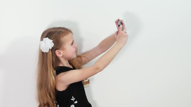 Cute Little girl makes selfie. Studio shot