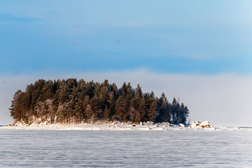 Pine-covered island in the snow and a frozen bay.