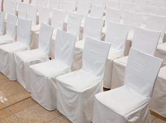 Eine Reihe Stühle mit Hussen aus weißem Stoff