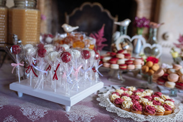 Obraz na płótnie Canvas Beautiful multi colored decorated baked sweet tasty candy bar dessert party with happy people around, catering banquet table. macaroons
