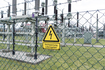 Fence of a transformer station with a yellow sign danger to life