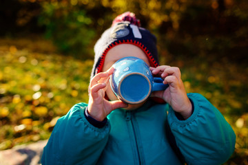 Fototapeta premium a young boy drinks from a cup at a picnic