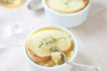 Small white bowls of onion soup with melted cheese toast and fresh thyme
