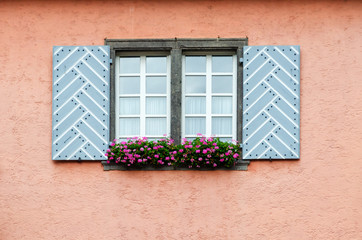Double window with shutters. Flowers on the windowsill. The wall is covered with plaster. Germany. City of Erfurt.