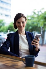 Portrait of businesswoman using mobile phone at counter