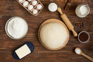 Ingredients for making cinnamon rolls on a wooden background