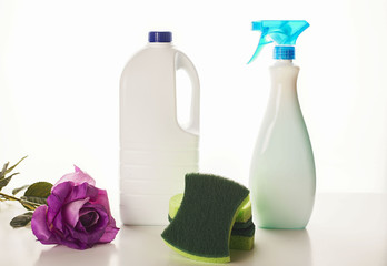 A lilac flower placed near the cleaning chemistry bottles and sponges